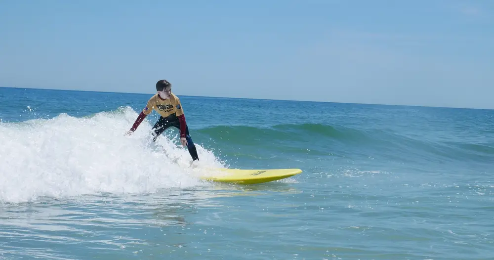 Child catches wave during surf lesson on LBI with South End Surf ‘N Paddle’s private surf instructors