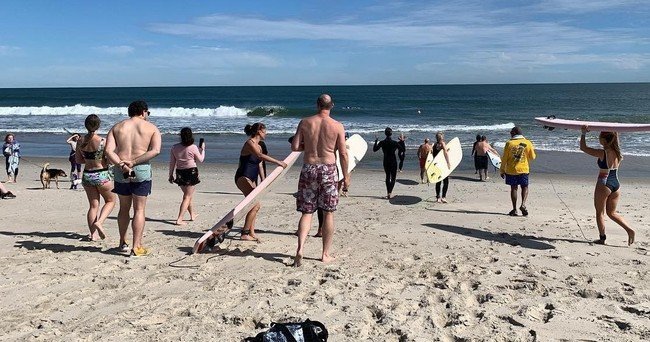 a group of people standing on top of a sandy beach