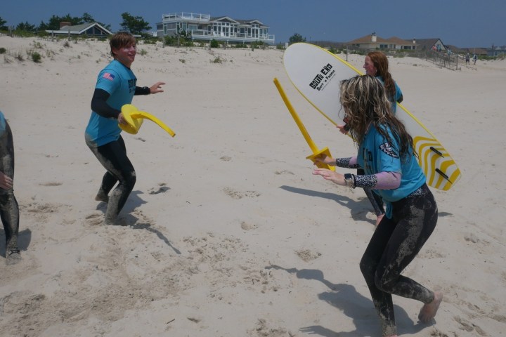 a group of people on a beach holding a surfboard