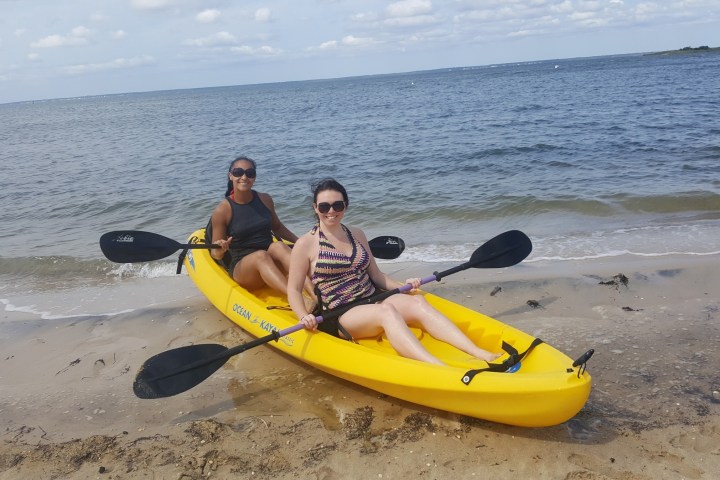 a person sitting on a beach holding a surfboard