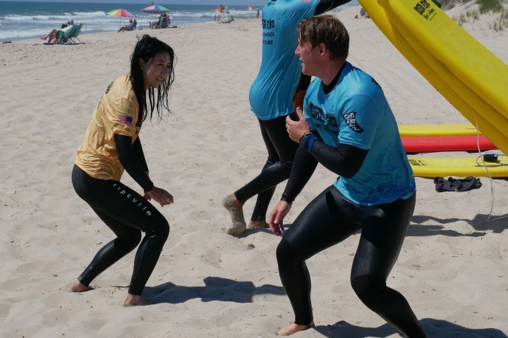 a group of people on a beach holding a surfboard