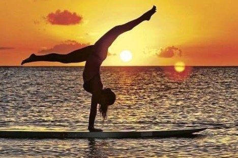 a person standing in front of a sunset over a body of water