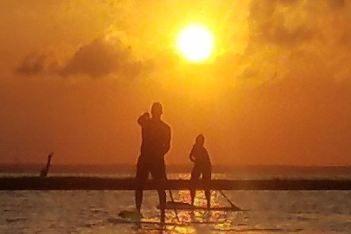 a person standing on a sandy beach with a sunset in the background