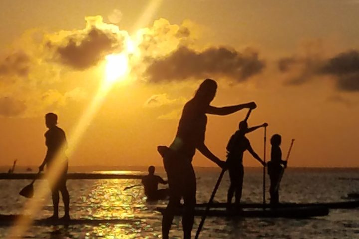 a group of people on a beach with a sunset in the background
