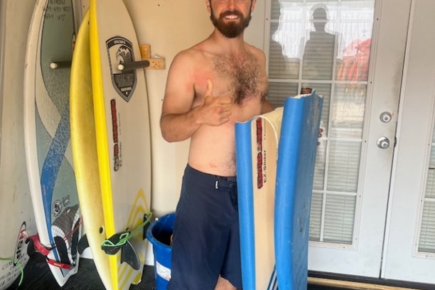 a young man wearing a wet suit holding a surfboard
