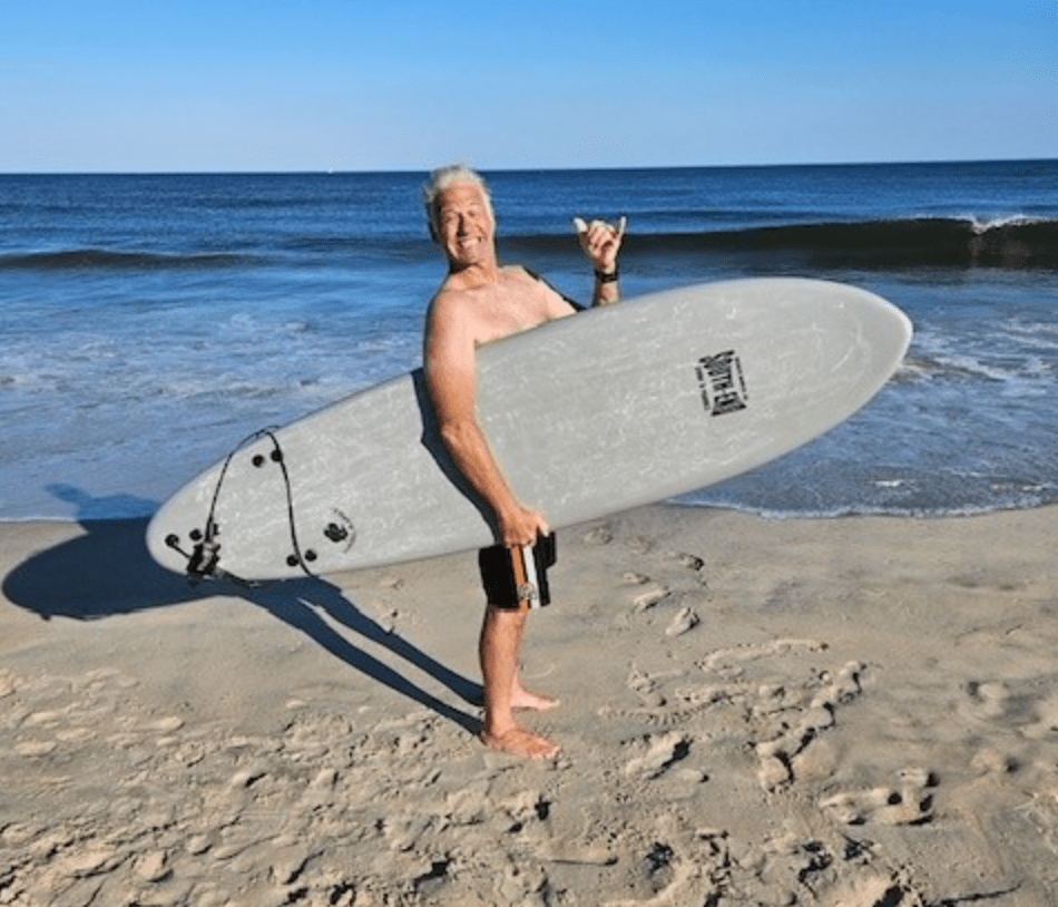 Screen+Shot+2024-01-22+at+3.35.35+PM a man carrying a surf board walking on a beach